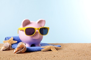 Piggy bank with sunglasses on beach